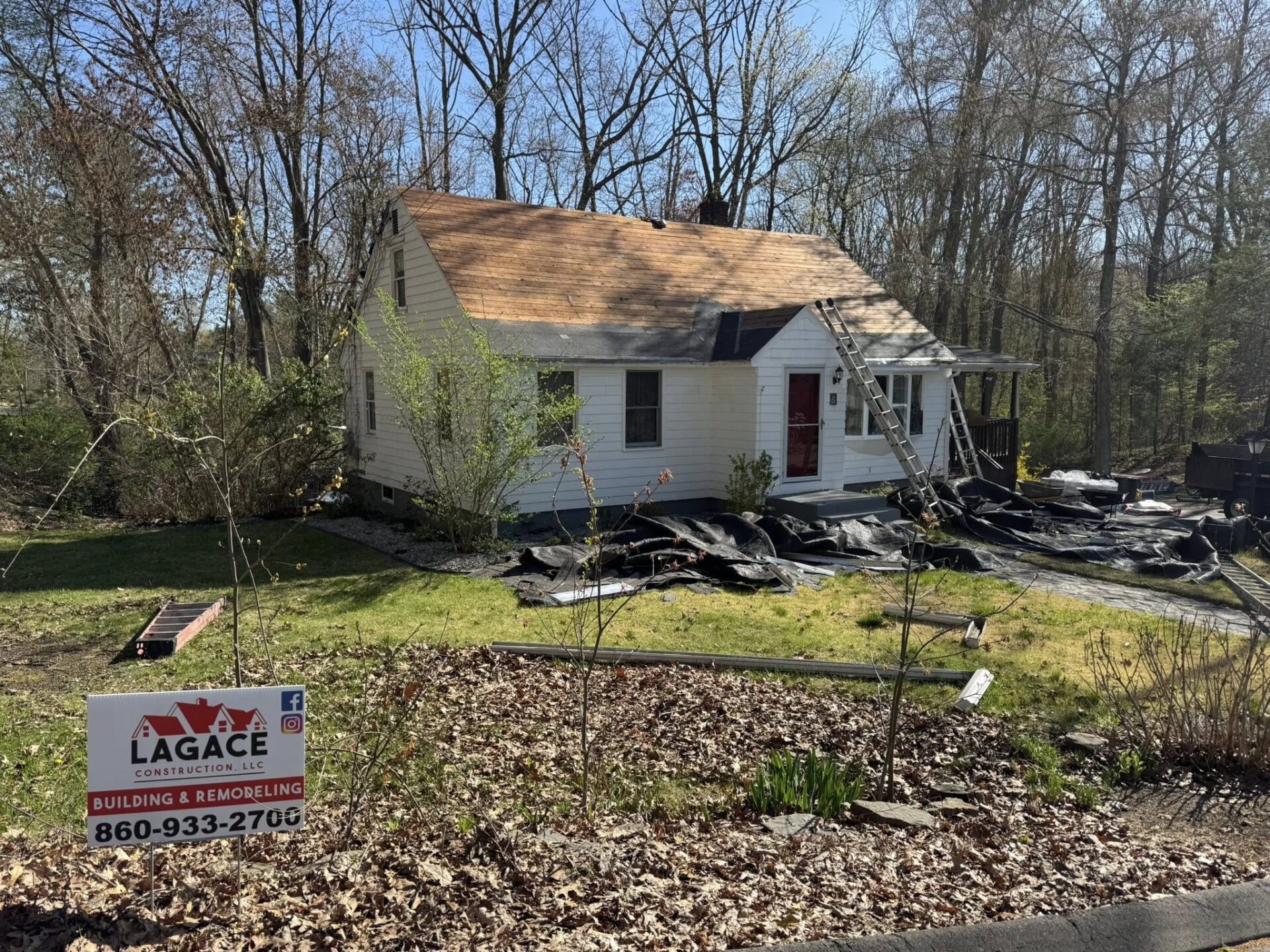 Lagace Construction replacing roof on white home in Andover, CT with visible branding sign and stripped shingles